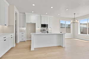 Kitchen with light countertops, recessed lighting, light wood-style flooring, tasteful backsplash, and white cabinets