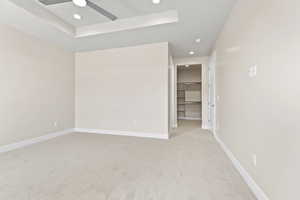 Unfurnished room featuring light colored carpet, a ceiling fan, recessed lighting, baseboards, and a raised ceiling