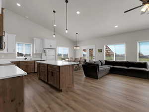 Kitchen featuring freestanding refrigerator, open floor plan, a ceiling fan, wood finished floors, and recessed lighting