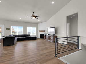 Living area featuring a ceiling fan, wood finished floors, a fireplace, recessed lighting, and vaulted ceiling