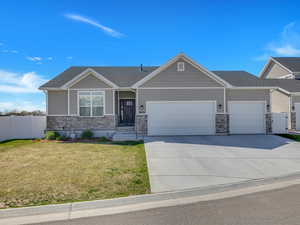 Craftsman inspired home with an attached garage, driveway, stone siding, and roof with shingles