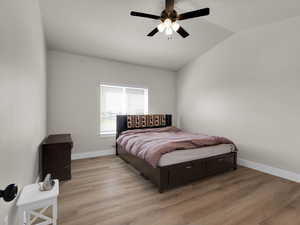 Bedroom featuring lofted ceiling, light wood finished floors, baseboards, and a ceiling fan