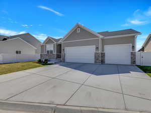 Craftsman house with a garage, driveway, and stone siding