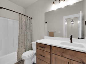 Full bath with toilet, vanity, and shower / bath combination with curtain