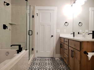 Full bathroom with double vanity, a stall shower, a bath, and baseboards