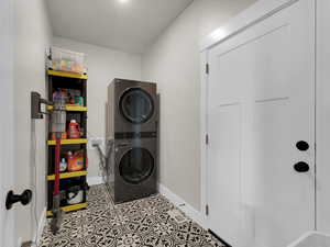 Laundry room with stacked washing machine and dryer and baseboards