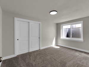 Unfurnished bedroom with carpet flooring, a closet, and baseboards