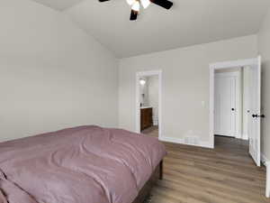 Bedroom with light wood-style flooring, lofted ceiling, baseboards, connected bathroom, and ceiling fan