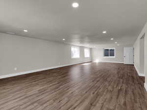 Unfurnished living room featuring dark wood finished floors, recessed lighting, and baseboards