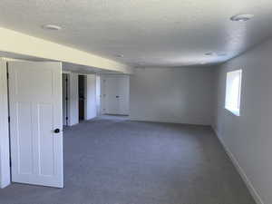 Carpeted empty room with a textured ceiling and baseboards