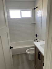 Full bath featuring toilet, wood finished floors, vanity, and bathing tub / shower combination