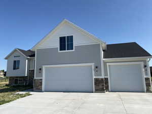 View of front of home with stone siding, driveway, and a garage