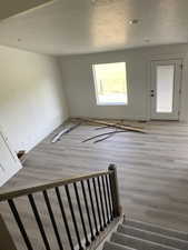 Stairway featuring wood finished floors, baseboards, a textured ceiling, and recessed lighting