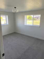 Carpeted spare room featuring a textured ceiling and baseboards