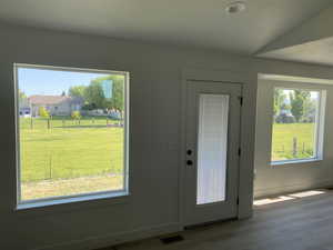 Doorway to outside with healthy amount of natural light, wood finished floors, and baseboards