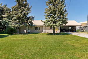Back of house featuring gravel driveway, metal roof, and a yard