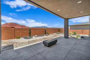 Fenced backyard with an outdoor fire pit, a patio area, and a mountain view