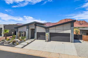 Modern home with a garage, a mountain view, driveway, stucco siding, and a gate
