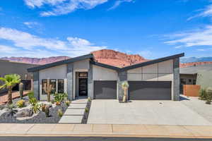 Contemporary home with a garage, a mountain view, driveway, and stucco siding