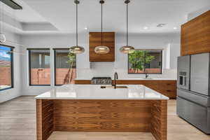 Kitchen with stainless steel fridge, modern cabinets, brown cabinets, a sink, and recessed lighting