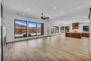 Unfurnished living room featuring a sink, a ceiling fan, light wood finished floors, recessed lighting, and baseboards
