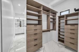 Spacious closet featuring light marble finish floors