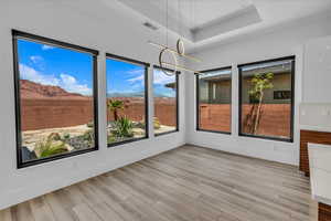 Unfurnished sunroom with plenty of natural light, a tray ceiling, and wood finished floors