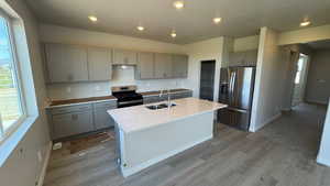 Kitchen with gray cabinets, stainless steel refrigerator with ice dispenser, gas stove, a sink, and a textured ceiling