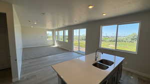 Kitchen featuring a sink, recessed lighting, baseboards, a textured ceiling, and wood finished floors