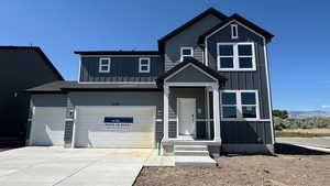 View of front of house with board and batten siding, driveway, an attached garage, and a mountain view