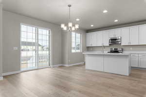 Kitchen with appliances with stainless steel finishes, baseboards, light countertops, a chandelier, and recessed lighting