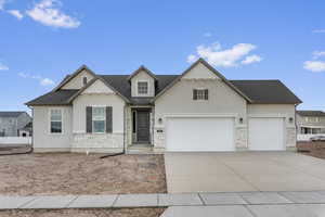 Traditional-style home with stucco siding, stone siding, driveway, an attached garage, and roof with shingles