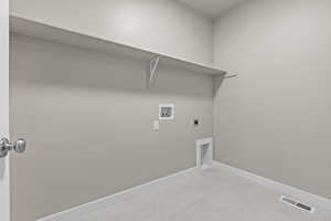 Washroom with hookup for a washing machine, hookup for an electric dryer, baseboards, and light tile patterned floors