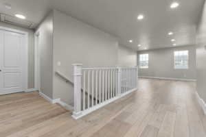 Hallway featuring an upstairs landing, recessed lighting, hardwood / wood-style floors, and baseboards
