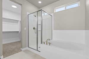 Full bath with a shower stall, a bath, a spacious closet, tile patterned floors, and baseboards