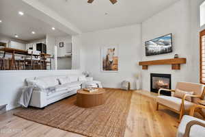 Living area featuring wood finished floors, a large fireplace, a ceiling fan, recessed lighting, and baseboards