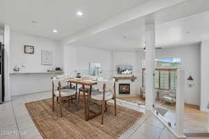 Dining room featuring light tile patterned floors, ceiling fan, a glass covered fireplace, recessed lighting, and baseboards