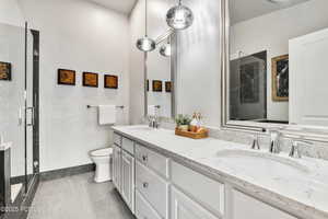 Bathroom with a shower stall, double vanity, and toilet