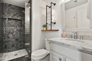Bathroom with vanity, toilet, and a stall shower