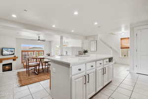 Kitchen featuring light tile patterned floors, a glass covered fireplace, recessed lighting, open floor plan, and a kitchen island