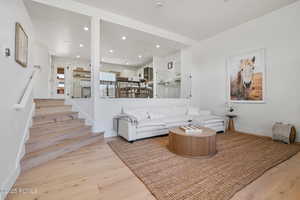 Living room with wood finished floors, stairs, baseboards, and recessed lighting