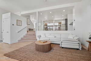Living room with light wood-style floors, stairs, recessed lighting, and baseboards