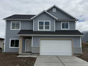 View of front of home with driveway, an attached garage, and roof with shingles