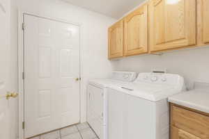Laundry room with cabinet space, washer and dryer, and light tile patterned flooring