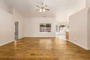 Unfurnished living room with a ceiling fan, wood-type flooring, arched walkways, and baseboards