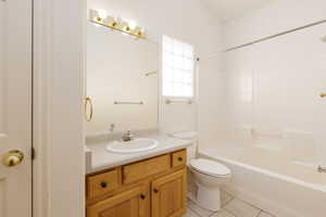 En-suite bathroom also with door to hallway featuring vanity, tile patterned floors, toilet, and shower / bathtub combination