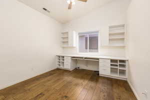 Bedroom/office featuring built in study area, dark wood finished floors, ceiling fan, baseboards, and vaulted ceiling