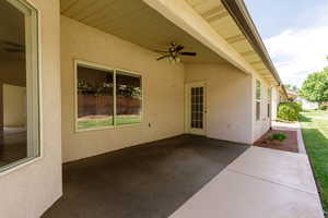 View of covered rear patio featuring a ceiling fan