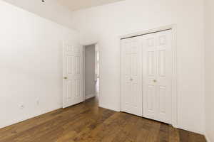 Bedroom/office featuring built in study area, dark wood finished floors, ceiling fan, baseboards, and vaulted ceiling and closet