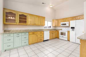 Kitchen with white appliances, high vaulted ceiling, glass insert cabinets, and granite countertops